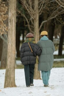 Two people walking arm in arm in a snowy park during winter
